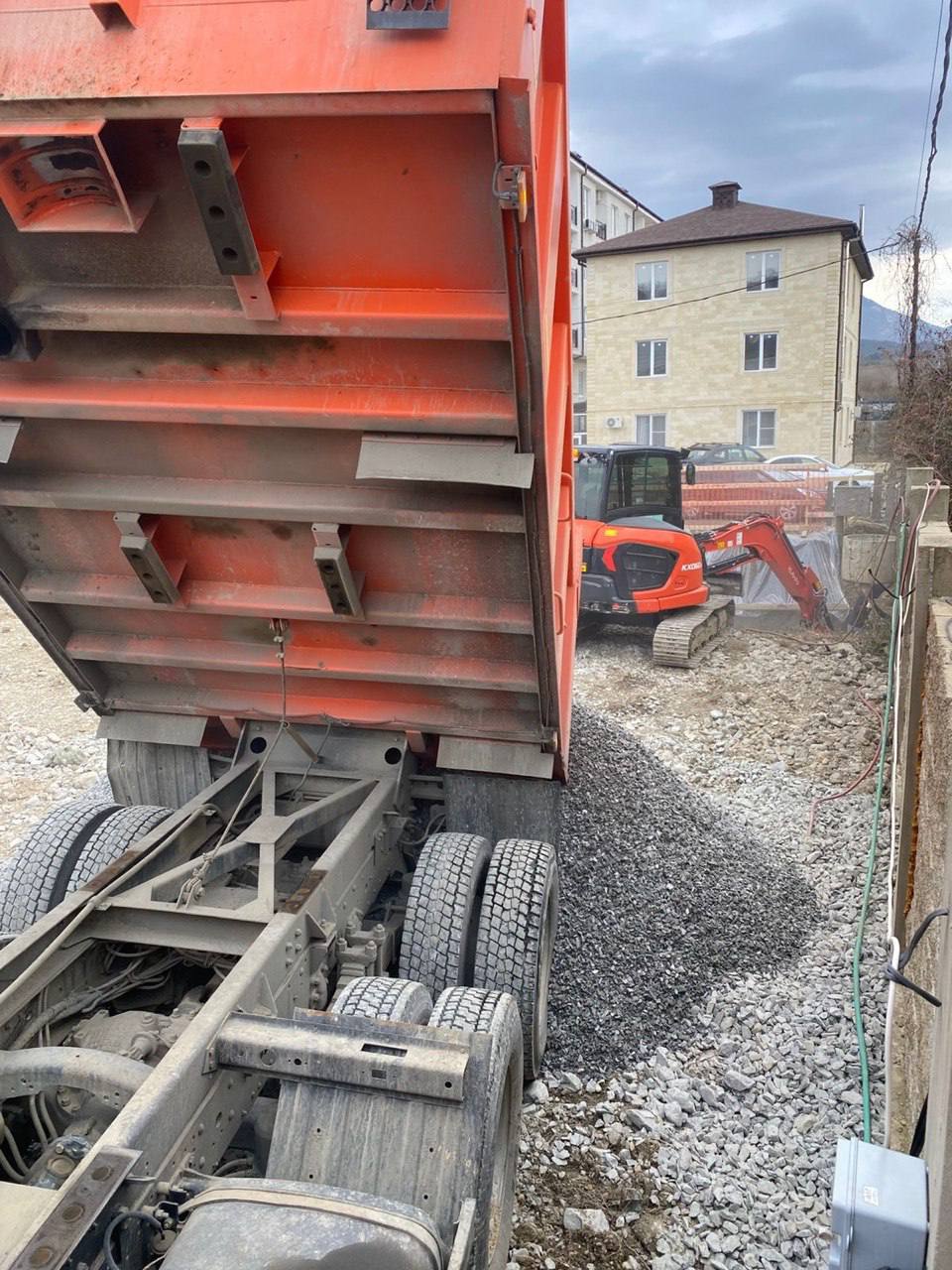 Выгрузка щебня с экскаватором на стройплощадке